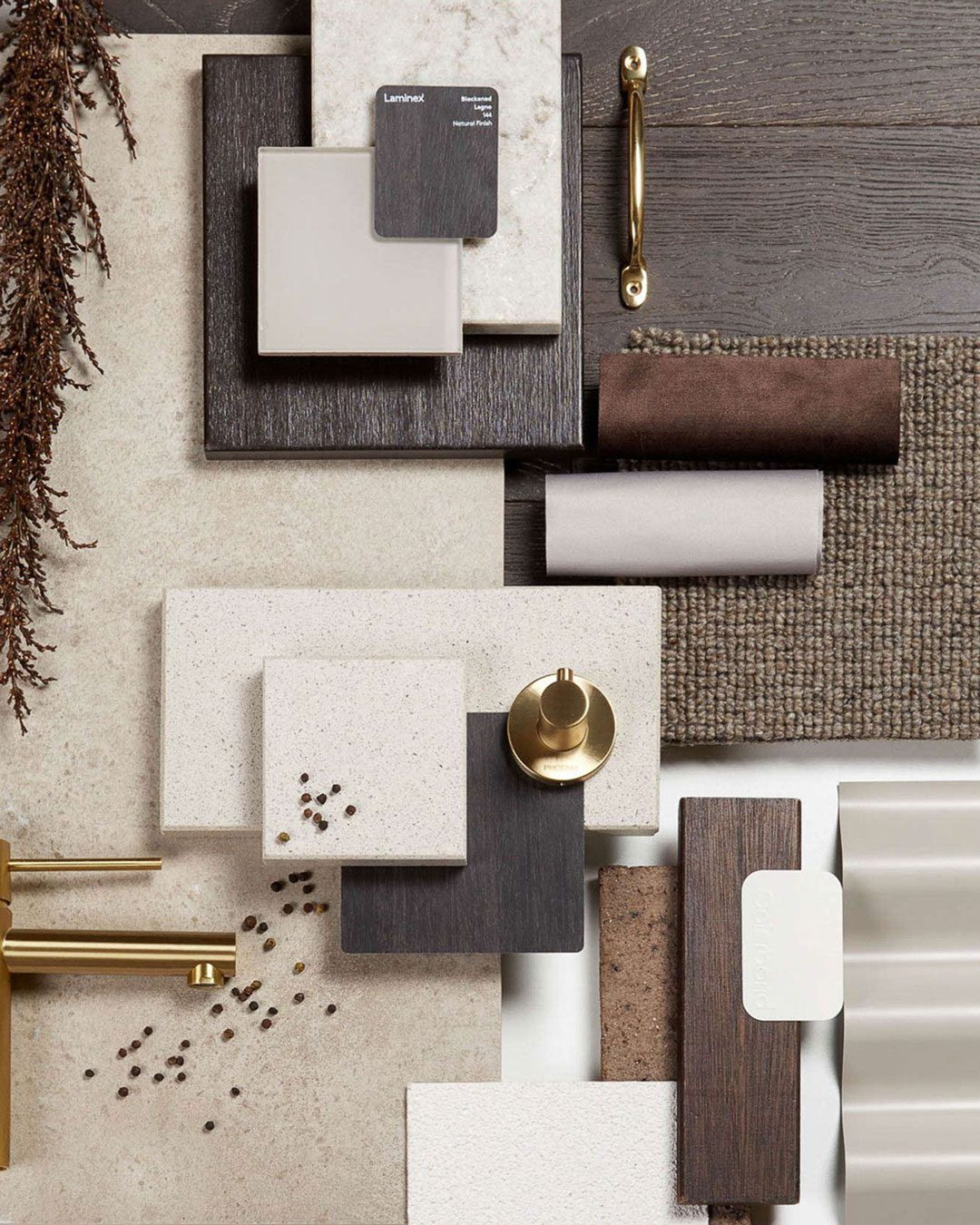finishselection Various material samples, including wood, laminate, fabric, and metal hardware, are arranged on a surface. Some dried plant stems and seeds are also included for decor.
