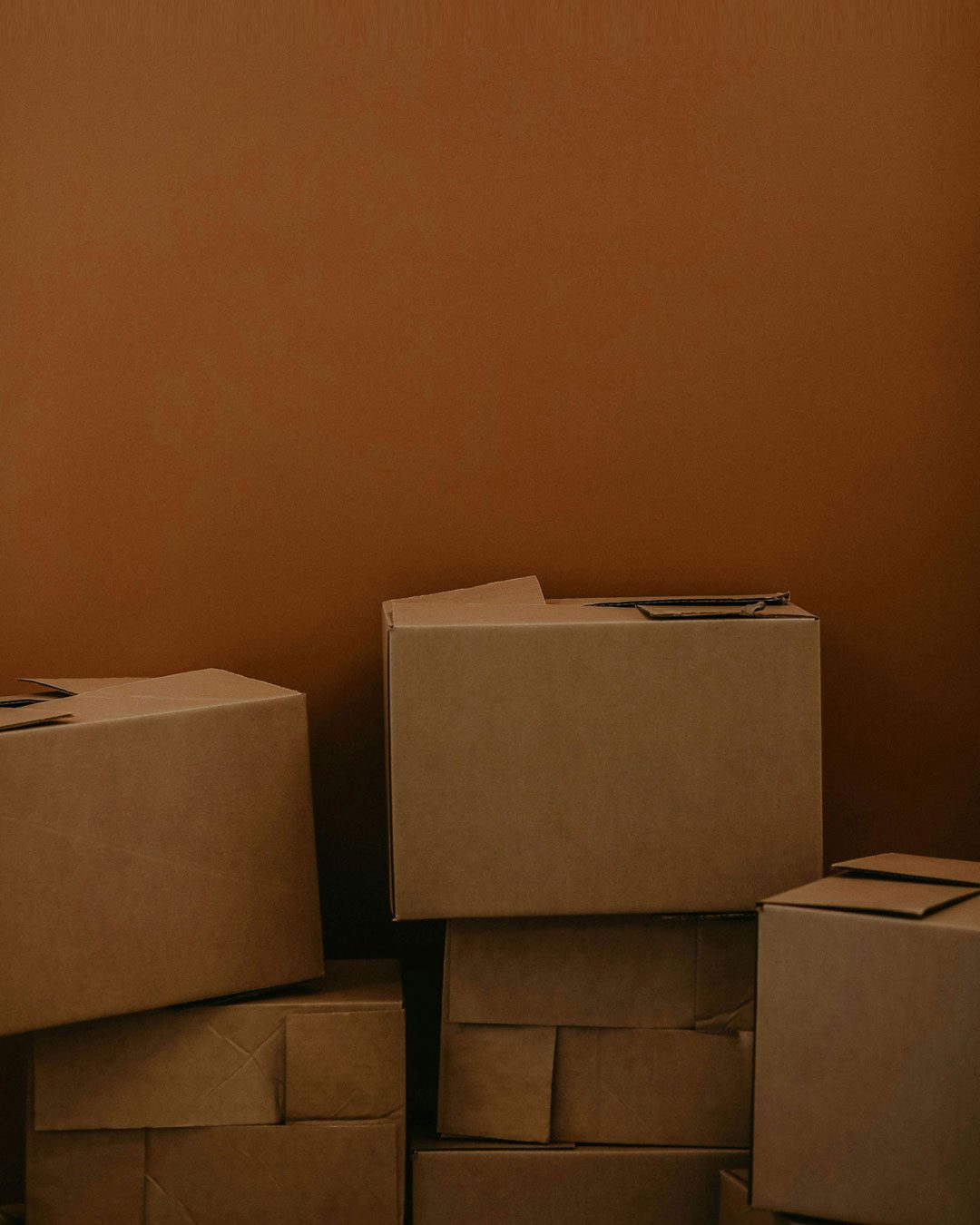 installation A stack of closed cardboard boxes against a plain brown background.